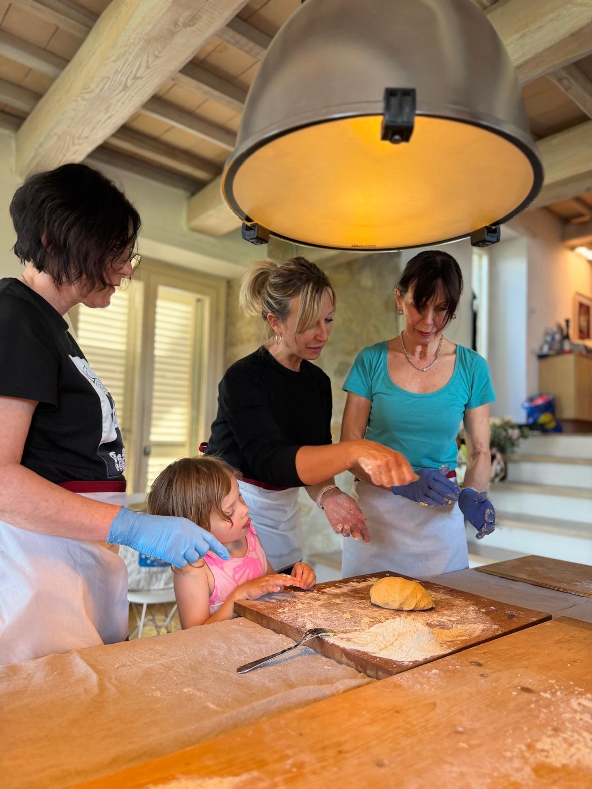 Tiziana leading a hands-on pasta cooking class with guests and a child